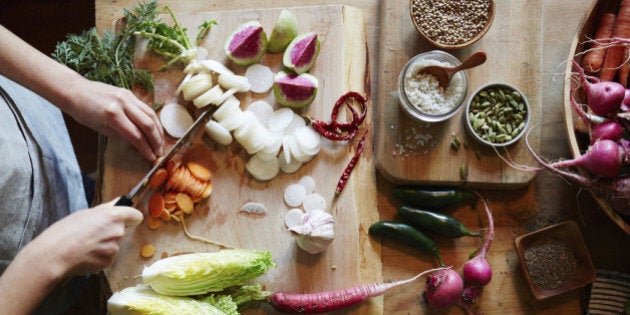 Woman cooking in kitchen with ingredients around her