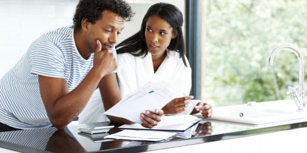 Portrait of worried young couple reading financial documents in kitchen
