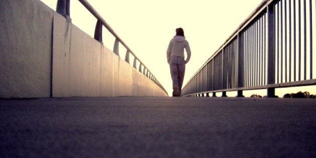 A lonely girl walking along bridge.