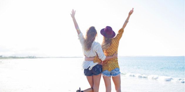 Two females arms raised on the beach