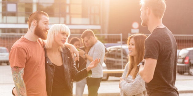 Two young couple talking outdoor on the street at sunset.