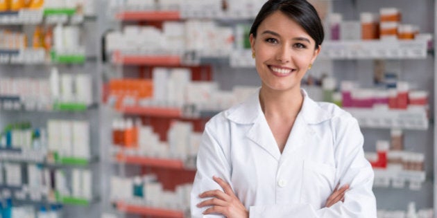 Portrait of a pharmacist working at the drugstore and looking at the camera smiling