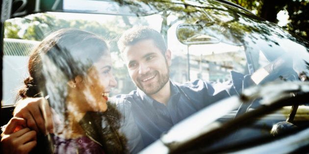 Smiling couple embracing in front seat of convertible