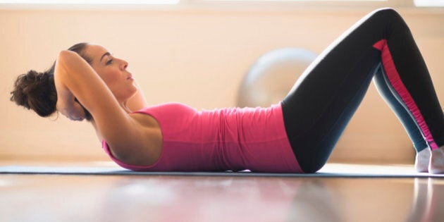 Close up of Hispanic woman doing sit-ups in gym