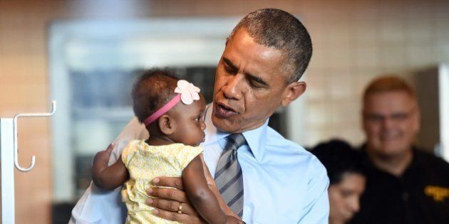 US President Barack Obama cradles a baby as he arrives July 17, 2014 at Charcoal Pit restaurant in Wilmington, Delaware to have lunch with a woman who wrote a letter to him. AFP PHOTO Jewel Samad (Photo credit should read JEWEL SAMAD/AFP/Getty Images)