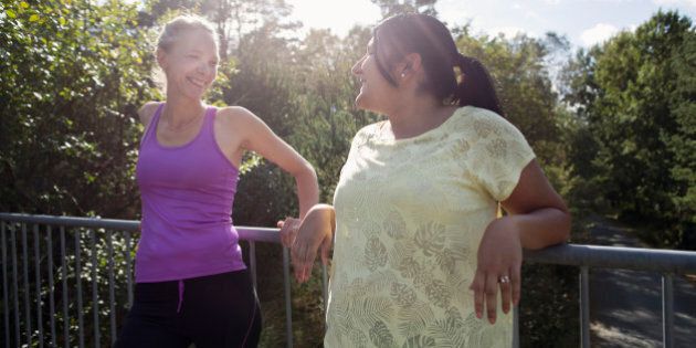Two female joggers resting againsst railing and talking