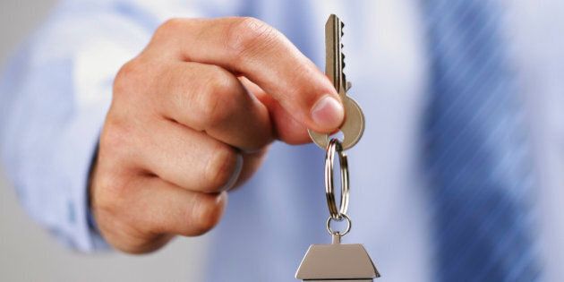 Holding out house keys on a house shaped keychain