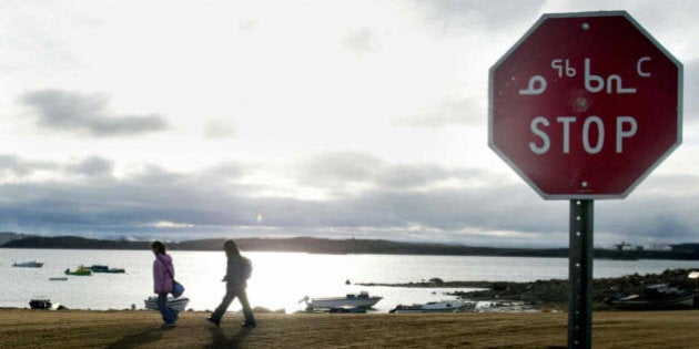 Iqaluit, CANADA: (FILES): This 02 October 2002 file photo shows two Inuit children returning from school in Iqaluit, northern Canada, past a stop sign written in both English and Inuit. Researchers from some 60 countries will try to better understand the Earth's poles in 2007 and the effect of climate change as part of the first 'International Polar Year' since the 1950s. The scientific effort, unlike previous undertakings, will be marked by the specter of global warming and transformed by collaboration with Inuits living in the Arctic. AFP PHOTO/FILES/Andre FORGET (Photo credit should read ANDRE FORGET/AFP/Getty Images)