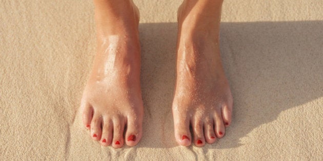 Close up of Hispanic woman's feet in sand on beach