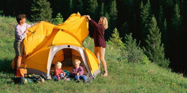 Mother and father pitching tent on mountain