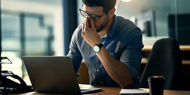 Shot of a young businessman experiencing stress during a late night at work