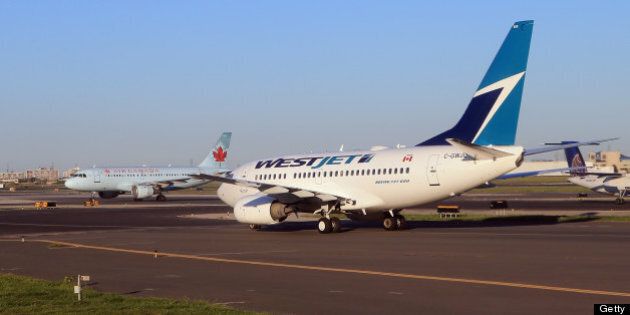 TORONTO, ON - AUGUST 28: A WestJet flight and an Air Canada flight cross paths on a runway at the Lester B. Pearson airport as photographed from an airplane on August 28, 2012 in Toronto, Canada. (Photo by Bruce Bennett/Getty Images)