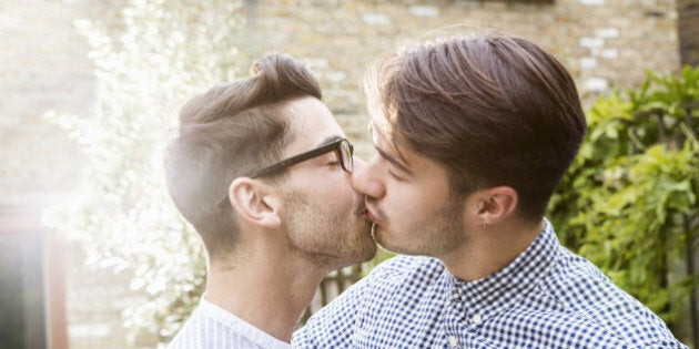 Gay couple kissing in garden.