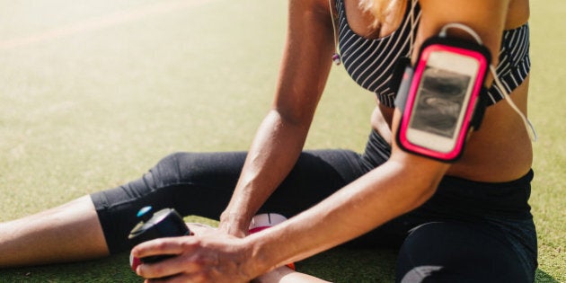 Tired woman relaxing on sports field after hard fitness workout.