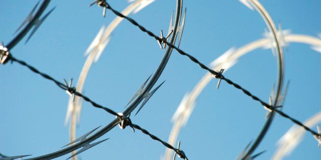 Razor and barbed wire topping a security fence