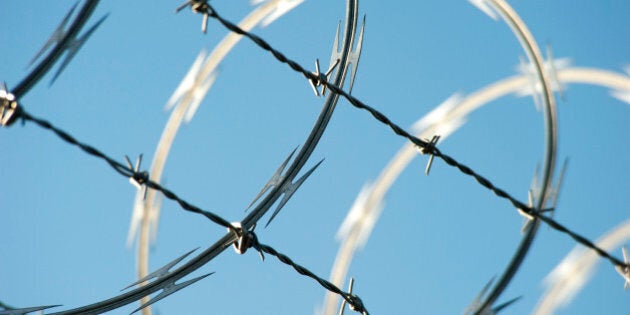 Razor and barbed wire topping a security fence