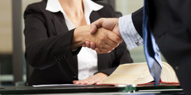 Mature female lawyer or notary with client in her office - handshake