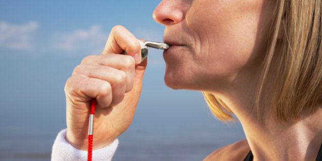 Woman blowing whistle on beach