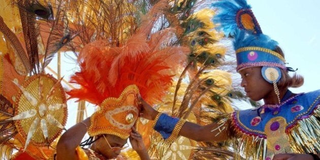 TORONTO, CANADA: Patricia Caterson (L) of Montreal gets a hand putting on her headgear from Jozette Reid (R) of Toronto while the pair prepare to enter the Toronto International Carnival Parade, formerly known as Caribana in Toronto, Canada 03 August, 2002. The annual weekend celebration of Caribbean culture is one of the world's largest, drawing nearly one million visitors to Toronto's streets and waterfront. AFP PHOTO/J.P. MOCZULSKI (Photo credit should read J.P. MOCZULSKI/AFP/Getty Images)