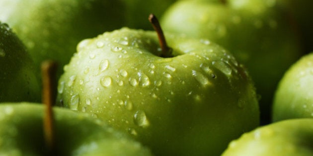 A tray full of healthy eating, crisp, wet and jucy green granny smith apples - each with their stalks on.