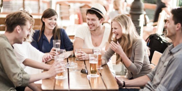 Group of young cheerful people having fun drinking beer outdoors.
