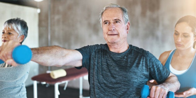 Shot of a senior man and woman using weights with the help of a physical therapist