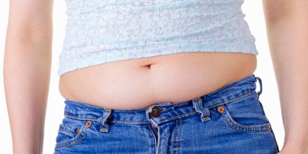 A woman's stomach bulging over the waistband of her jeans.