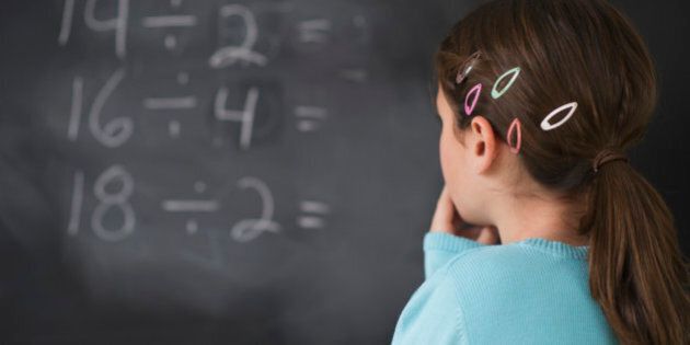 Girl looking at math equations on blackboard