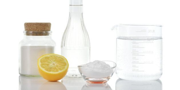 Eco-friendly natural cleaners. Vinegar, baking soda, salt, lemon and water in measuring cup on white background. Homemade green cleaning.