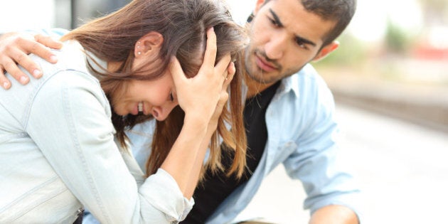 Side view of a muslim man comforting a sad caucasian girl mourning in a train station