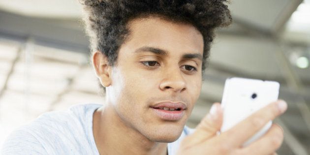 young man looking at mobile at station