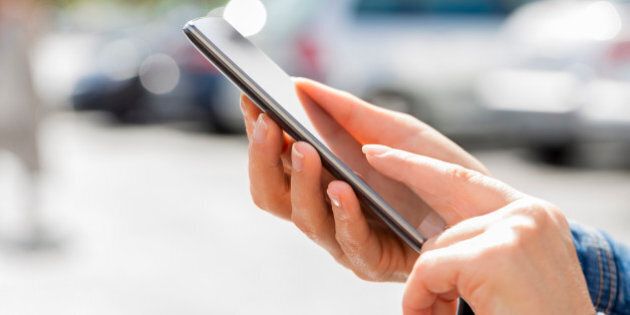 Female's hand using smartphone to find her car in a parking outside
