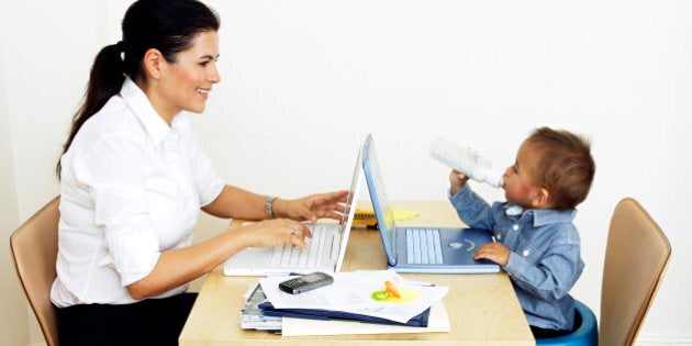 woman working from home sitting at table with little son