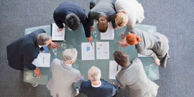 Business people huddled around paperwork on table