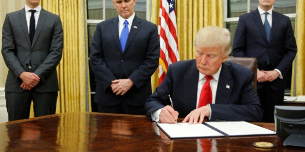 U.S. President Donald Trump, flanked by Senior Advisor Jared Kushner (standing, L-R), Vice President Mike Pence and Staff Secretary Rob Porter welcomes reporters into the Oval Office for him to sign his first executive orders at the White House in Washington, U.S. January 20, 2017. REUTERS/Jonathan Ernst TPX IMAGES OF THE DAY