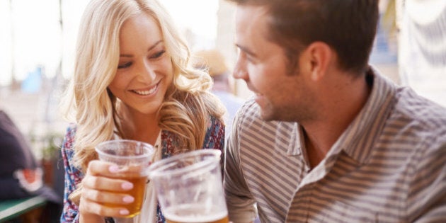 romantic couple drinking beer in plastic cups at outdoor bar with lens flare