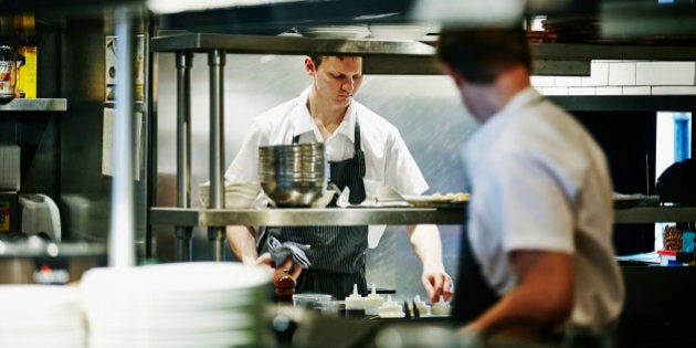 Sous chef preparing ingredients at workstation in restaurant kitchen before dinner service