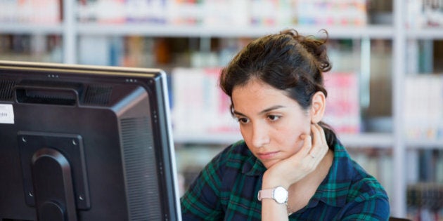 Young working/studying online on a computer at Library.