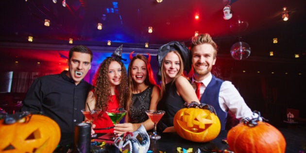 Young people posing in Halloween hats and with pumpkins