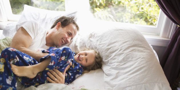Father and Daughter Playing On Bed