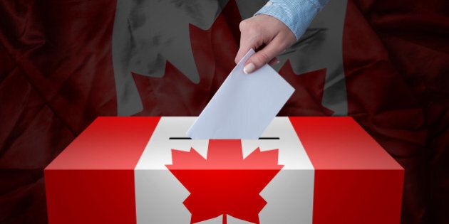 A hand casting a vote in a ballot box for an election in the Canada
