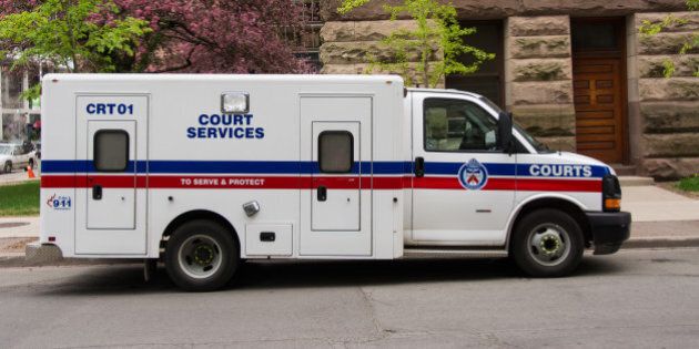 TORONTO, ONTARIO, CANADA - 2015/05/13: Toronto Court Services van. The white van has the words 'Court Services' in the center in blue, along with the word 'Courts' in white on a blue stripe that sits over a red one. The truck is in front of a brown stone building and some flowering trees. (Photo by Roberto Machado Noa/LightRocket via Getty Images)