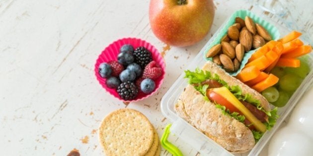 School lunch box with books and pencils in front of black board, copy space