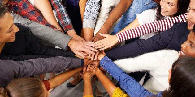 Shot of a diverse group of business people joining their hands in a symbol of unity