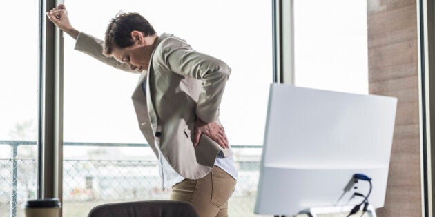 Businesswoman at the window holding her back