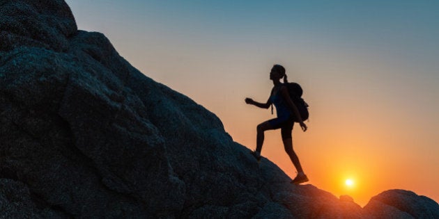 Lady walking on the rocks at sunset