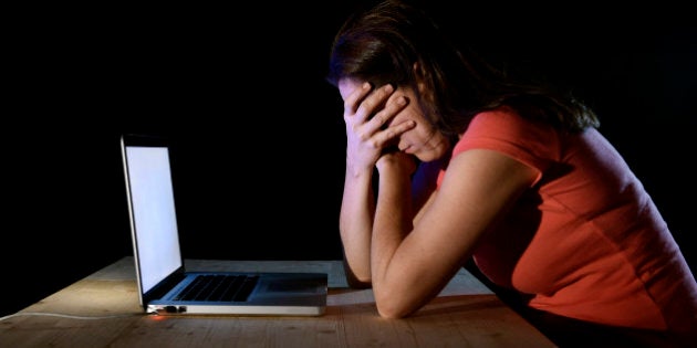 young desperate and depressed freelance worker or student woman working with computer laptop alone late at night in stress suffering internet bullying victim of social network