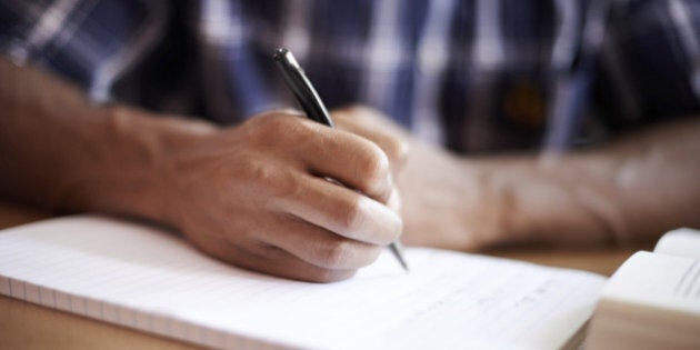 Closeup shot of a young student writing on a note pad