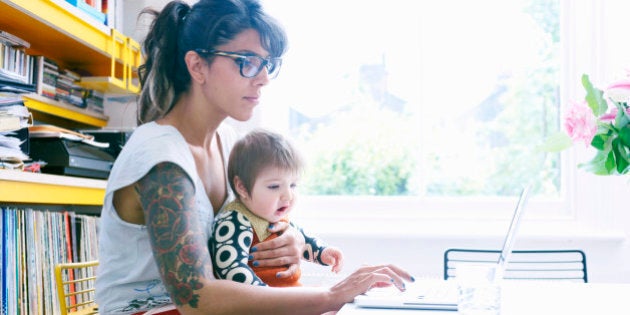 mother with baby in lap working on laptop at home