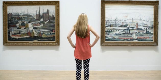 An employee poses for a picture in front of English artist Laurence Stephen Lowry's paintings 'Industrial Landscape (Ashton Under Lyne 1952) (L) and 'Industrial Landscape 1955' (R) at the Lowry and the Painting of Modern Life exhibition at Tate Britain in London on June 24, 2013. The exhibition runs from June 26 - October 20. AFP PHOTO/JUSTIN TALLIS == RESTRICTED TO EDITORIAL USE, MANDATORY MENTION OF THE ARTIST UPON PUBLICATION, TO ILLUSTRATE THE EVENT AS SPECIFIED IN THE CAPTION == (Photo credit should read JUSTIN TALLIS/AFP/Getty Images)